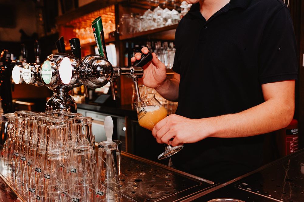 Medewerker tapt bier aan de bar van Stadtlander, tapkranen met Brand Weizener en La Chouffe