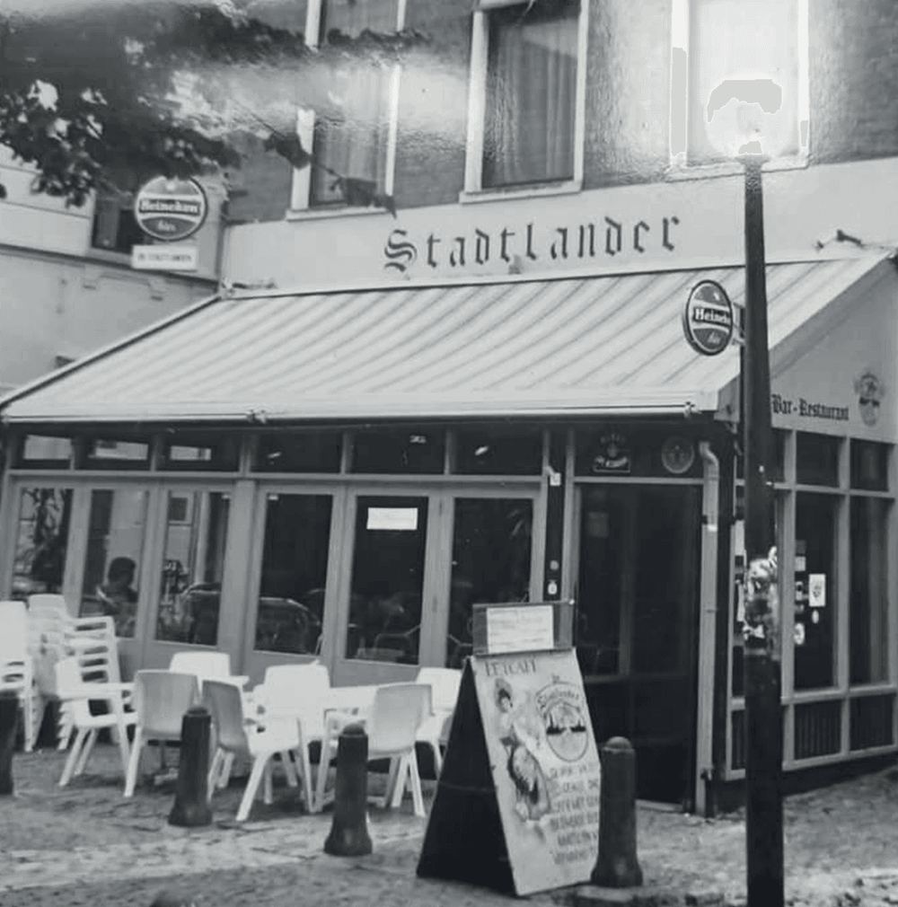 De gevel van Stadtlander in vroeger jaren, met luifel, terrasstoelen en een Heineken-uithangbord